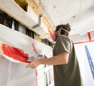 Man Wearing Respirator Inspects Home Construction Site after Mold Remediation
